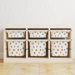A IKES TRofast storage organiser with six cubby bins, each containing a white fabric storage bag printed with colourful alphabet letters, set against a plain white wall and light wood floor.
