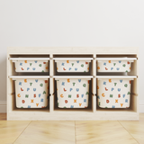 A IKES TRofast storage organiser with six cubby bins, each containing a white fabric storage bag printed with colourful alphabet letters, set against a plain white wall and light wood floor.