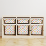 A light wood storage organizer with six cubby shelves holding six pastel checkered bins, set against a plain white wall and light wood floor.