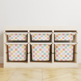 A light wood storage organizer with six cubby shelves holding six pastel checkered bins, set against a plain white wall and light wood floor.