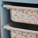 Floral-patterned storage bins stacked against a light blue cabinet.