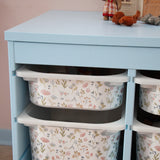Light blue cabinet with floral-patterned storage bins on a neutral background