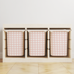 Wooden storage unit with three pink checkered bins on a light wooden floor.