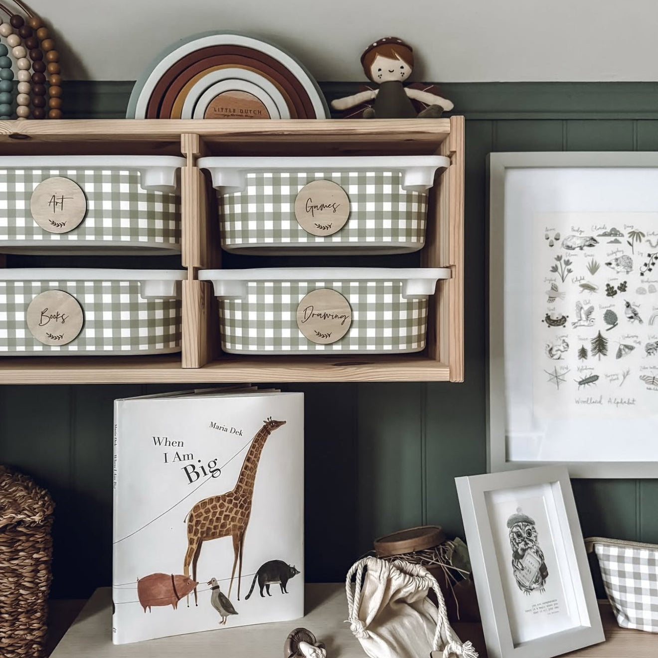 Nest of wooden baskets with checkered patterns on a shelf, accompanied by a book and framed picture.
