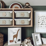 Nest of wooden baskets with checkered patterns on a shelf, accompanied by a book and framed picture.