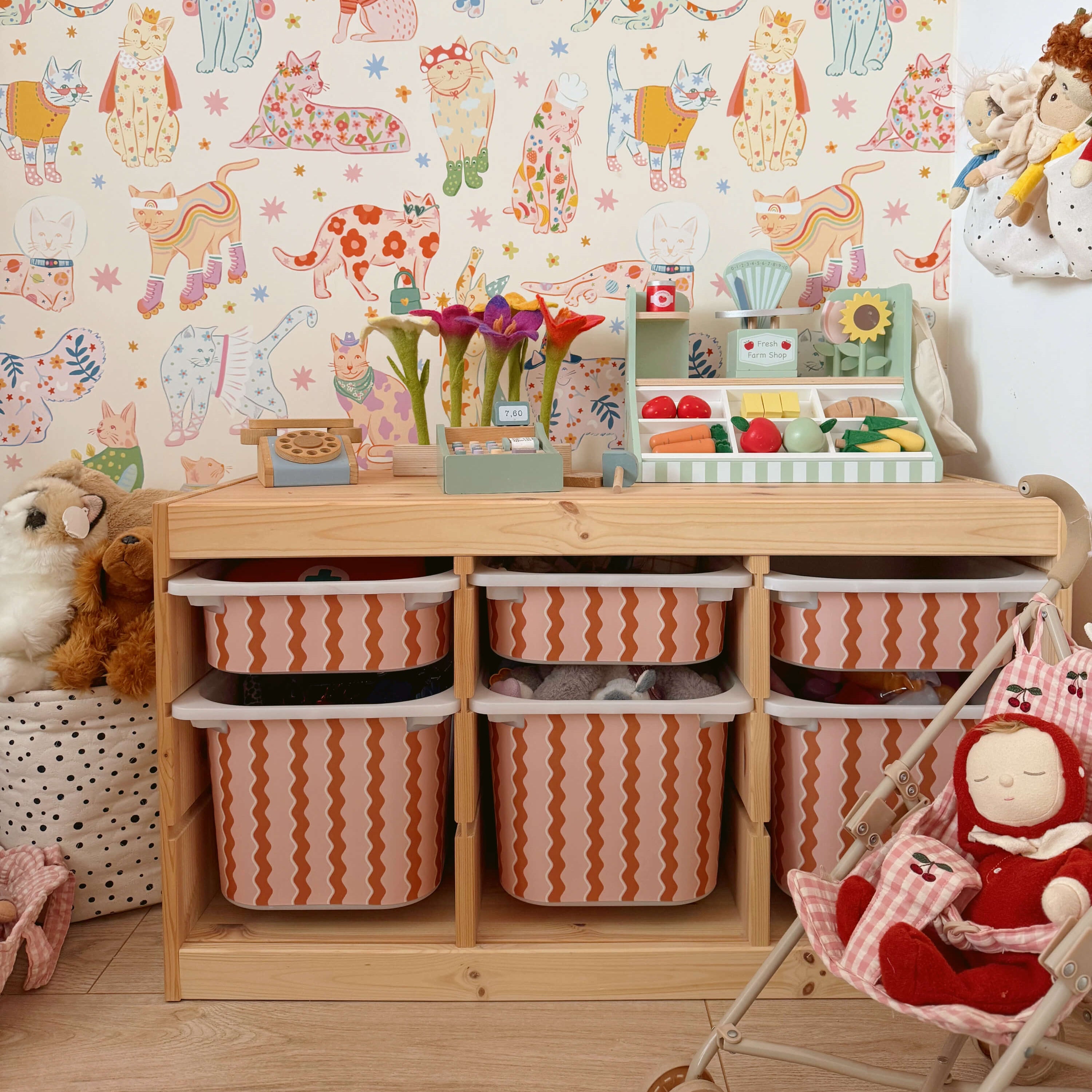 Children's room with IKEA Trofast unit wooden shelf, colorful wallpaper, and toys.