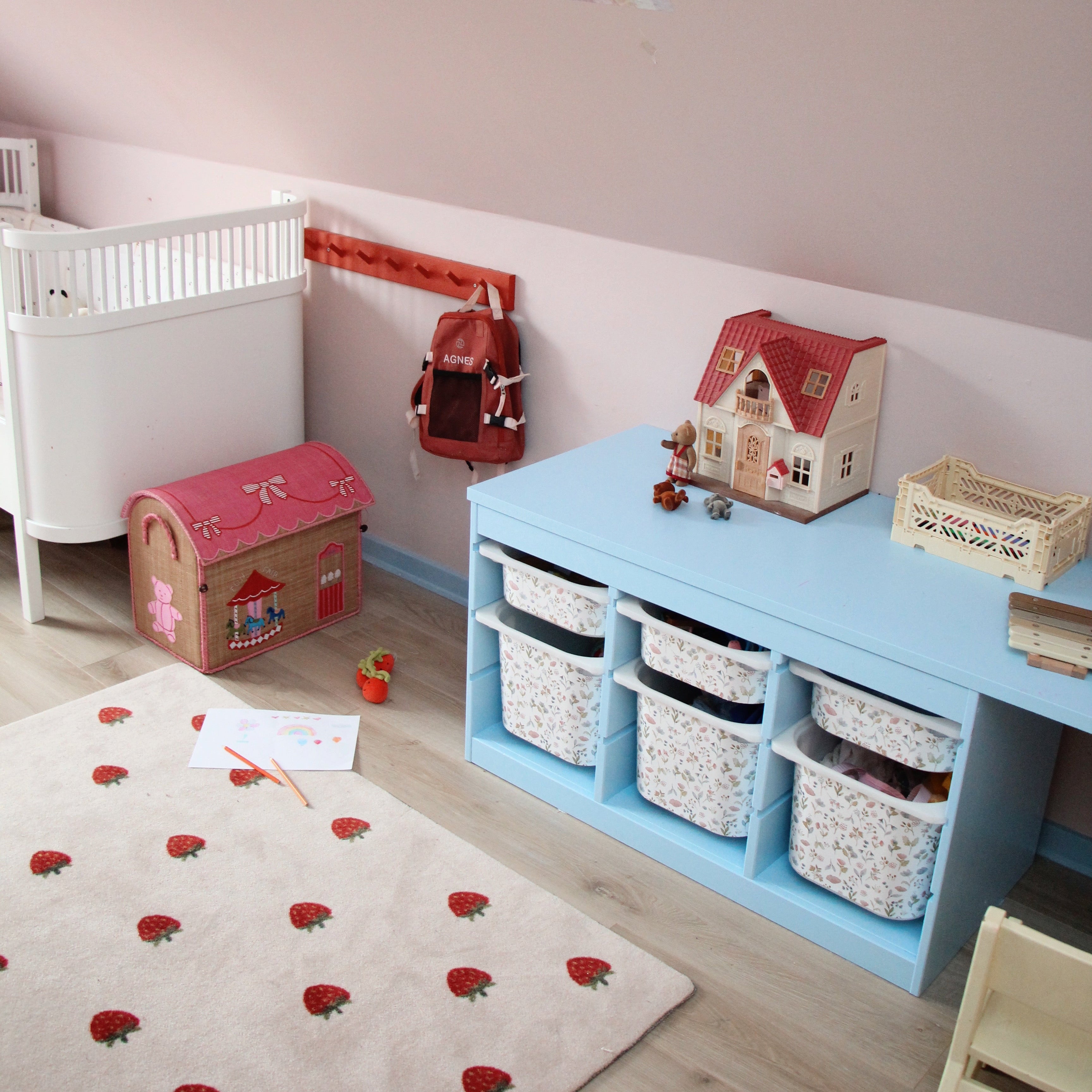Children's room with a blue desk, toy storage, and a crib.