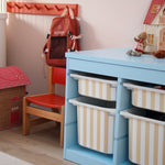 Children's room with a blue storage unit, red chair, and toys.