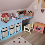 Children's playroom with a small desk, toys, and colorful storage bins.