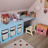 Children's playroom with a small desk, toys, and colorful storage bins.