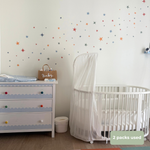A nursery room scene showing a white dresser and white crib with a white canopy, decorated with scattered star wall decals in multiple colors on a white wall. A small brown bag labeled 'Baby' sits on the dresser, and a green text bubble in the corner reads '2 packs used'.