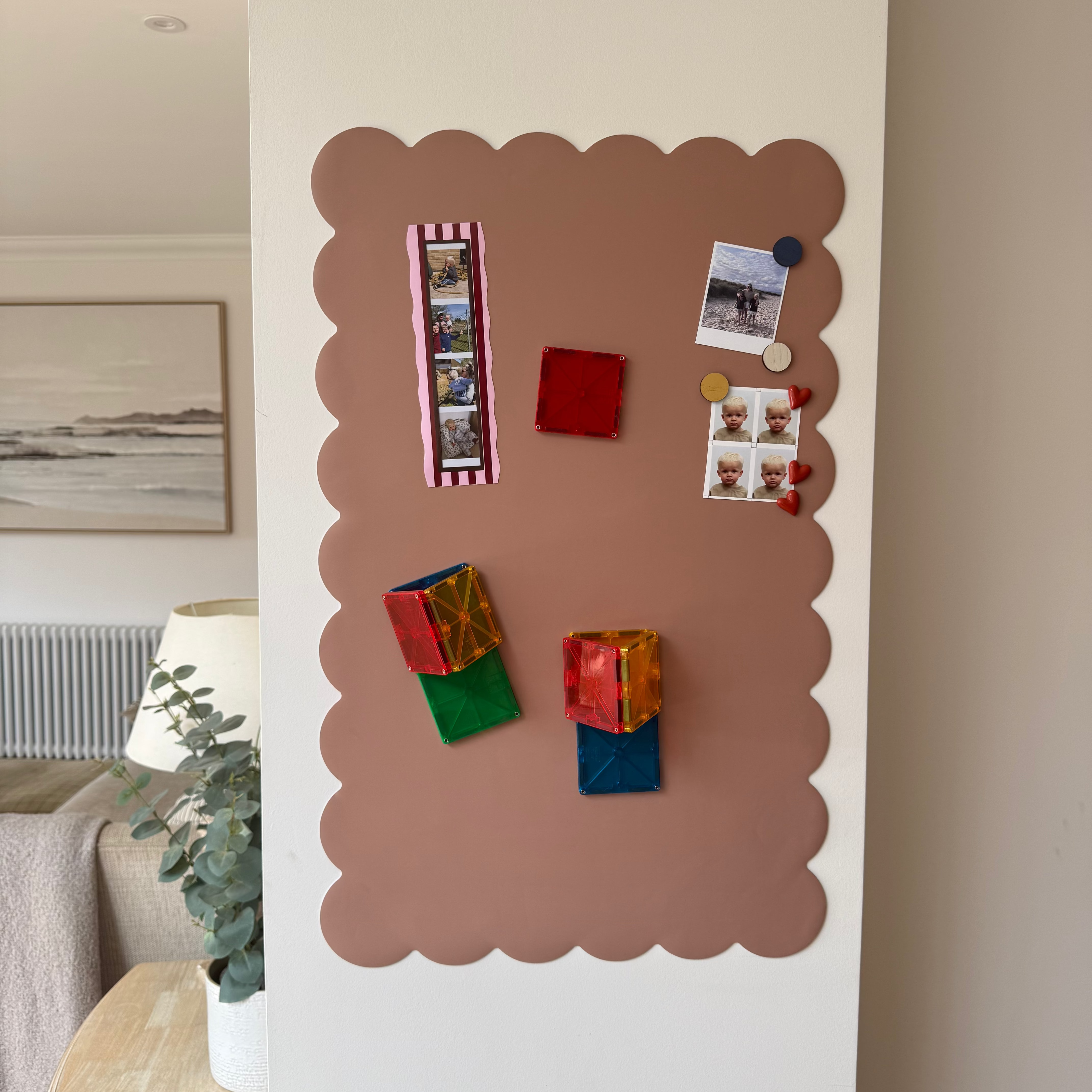 Magnetic board with colorful magnets and photos on a wall in a living room.